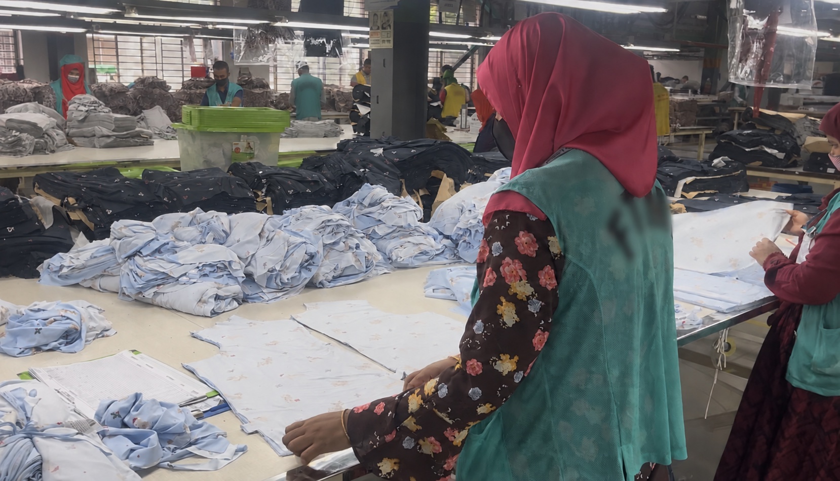 Workers manually checking and tagging stacks of cut garment panels